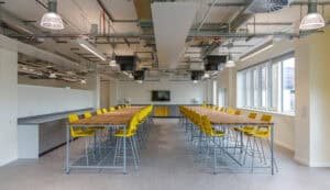 Two rows of tables with chairs in an exposed ceiling classroom