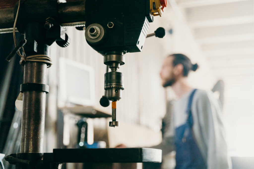 Close-up on machinery in a toolroom with a man dressed in overalls in the distance - out of focus
